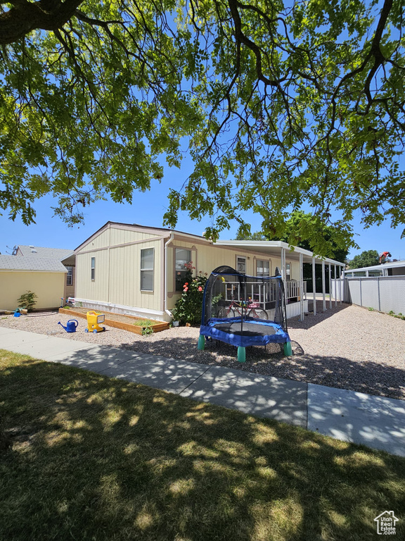 Rear view of property featuring a yard and a trampoline