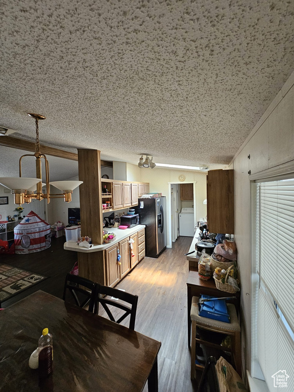 Living room with washer / dryer, light hardwood / wood-style floors, and a textured ceiling