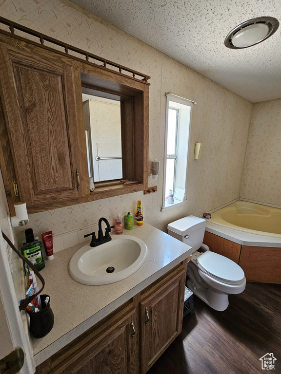 Full bathroom featuring a textured ceiling, washtub / shower combination, hardwood / wood-style flooring, vanity, and toilet