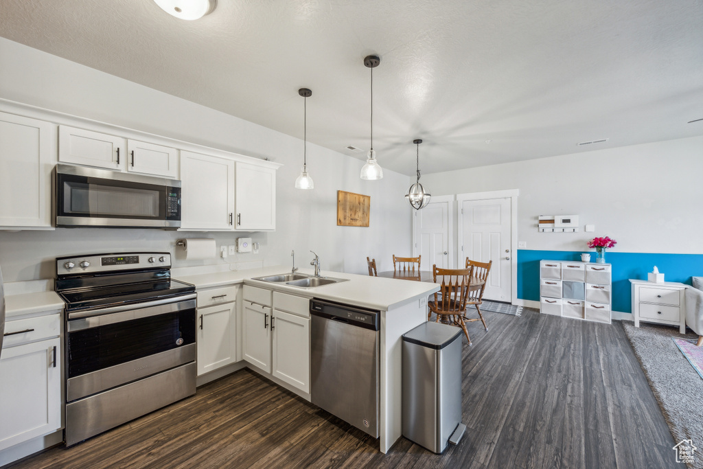 Kitchen featuring white cabinetry, dark wood-type flooring, stainless steel appliances, kitchen peninsula, and sink