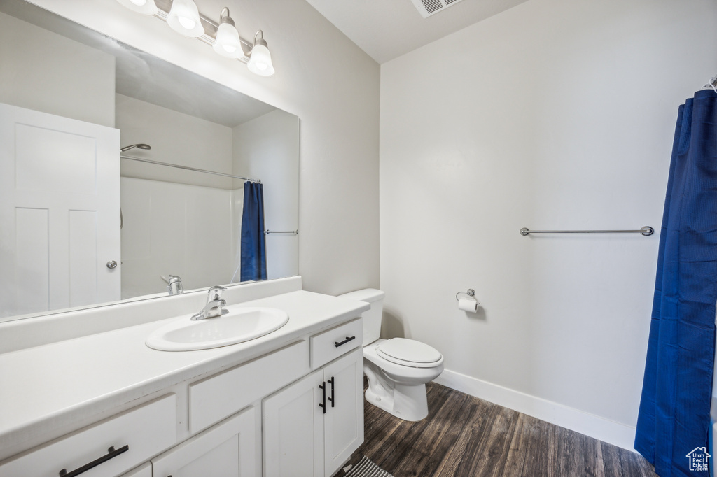 Bathroom featuring vanity with extensive cabinet space, toilet, and hardwood / wood-style floors