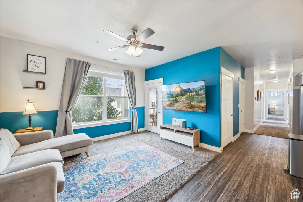 Living room featuring ceiling fan and dark wood-type flooring