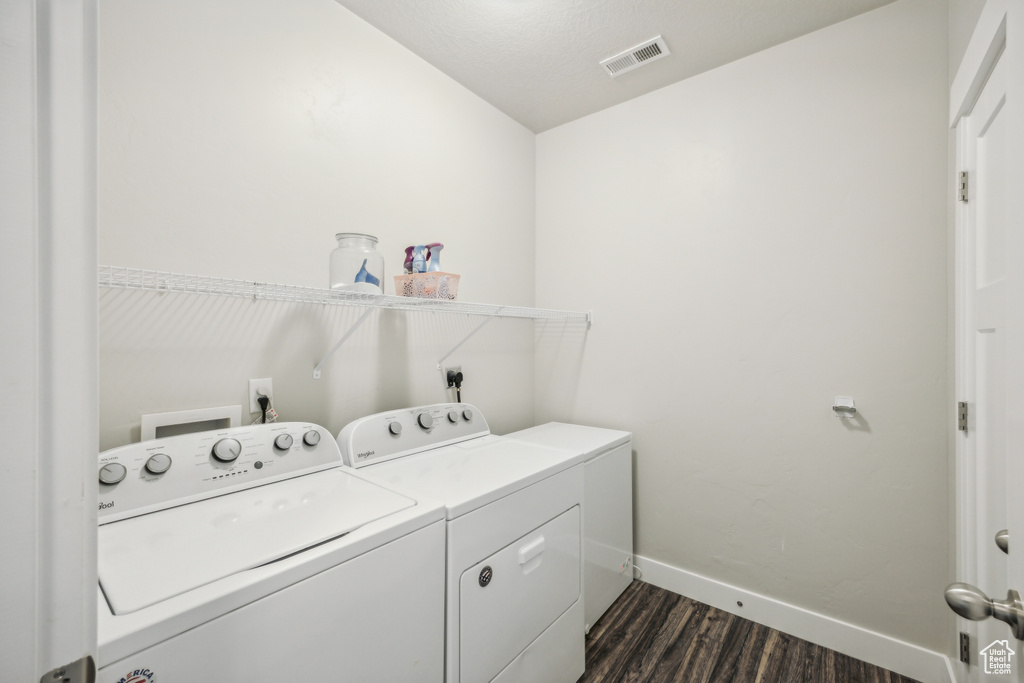 Clothes washing area featuring dark wood-type flooring, washer and clothes dryer, and washer hookup