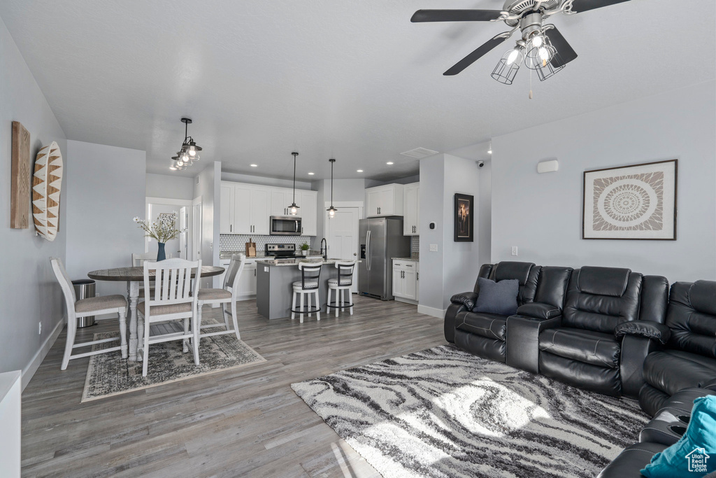 Living room with ceiling fan, light wood-type flooring, and sink