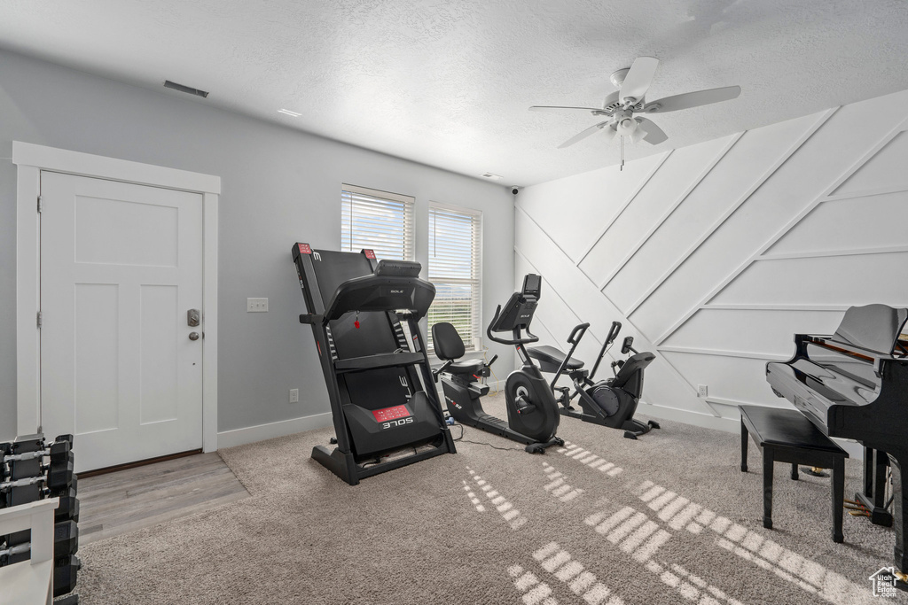 Workout area with hardwood / wood-style floors, ceiling fan, and a textured ceiling