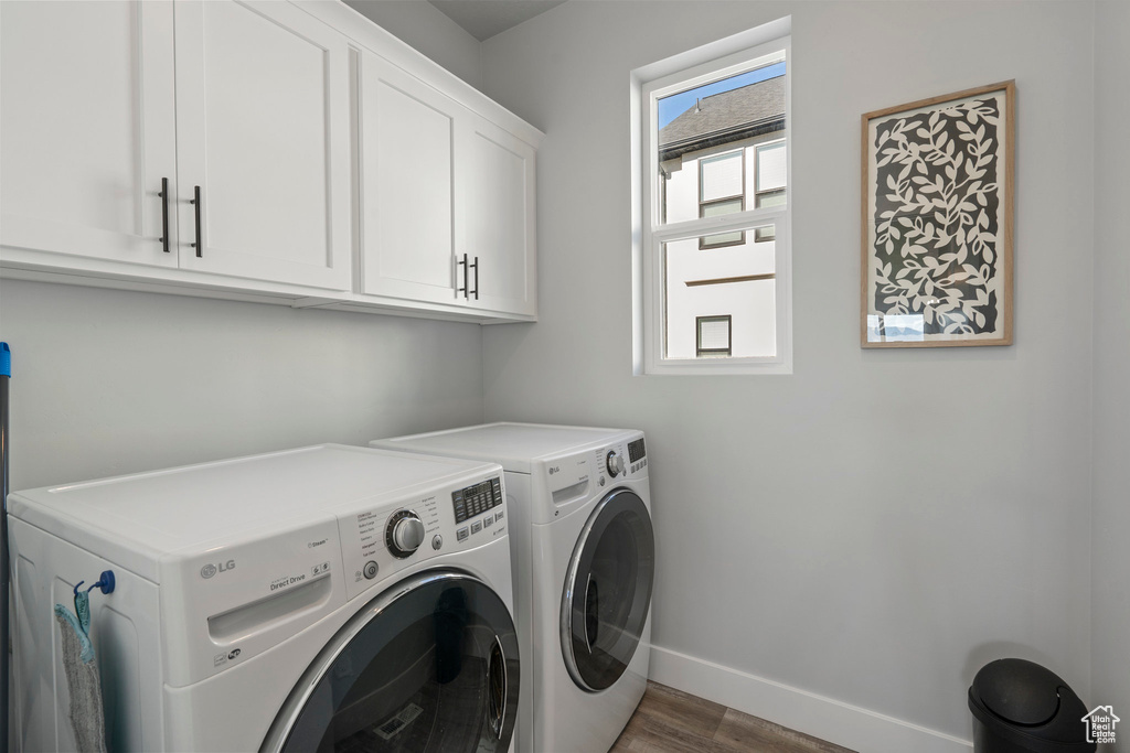 Laundry room with washer and dryer, cabinets, and dark wood-type flooring