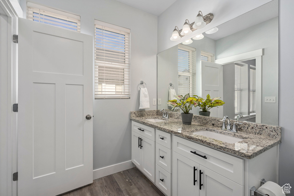 Bathroom featuring vanity with extensive cabinet space, dual sinks, and hardwood / wood-style flooring