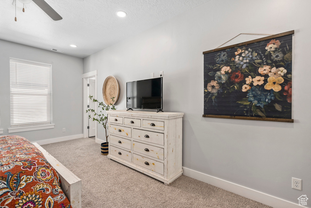 Carpeted bedroom featuring ceiling fan and a textured ceiling