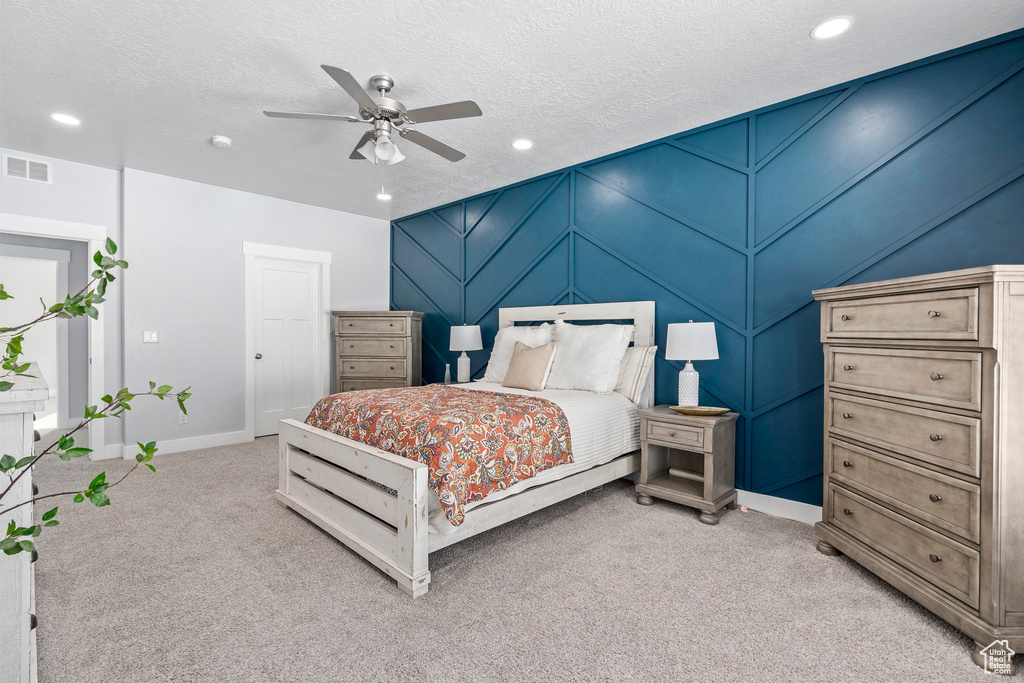 Bedroom with ceiling fan, a textured ceiling, and light colored carpet