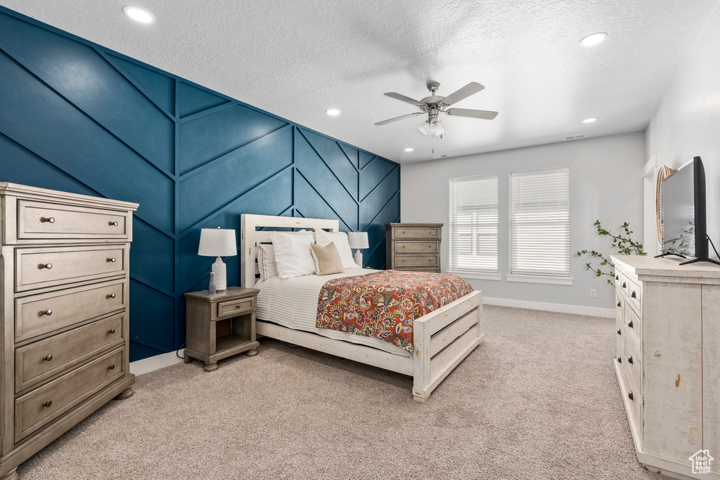 Carpeted bedroom with ceiling fan and a textured ceiling