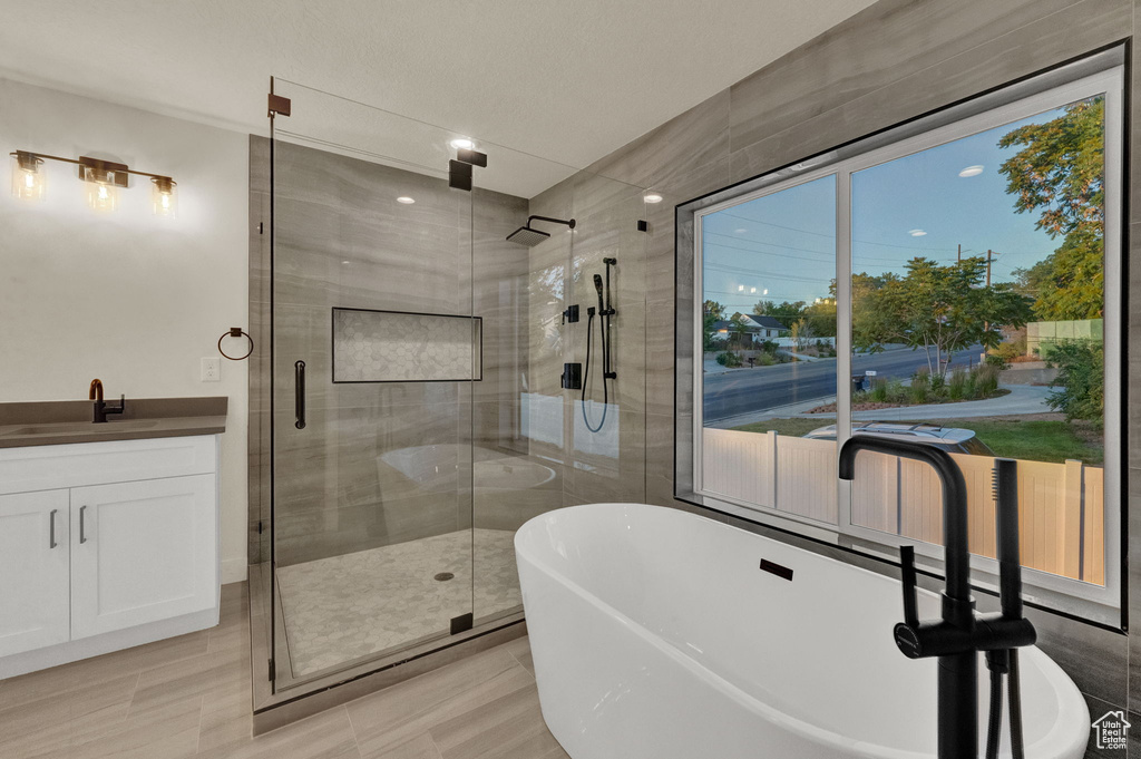 Bathroom featuring shower with separate bathtub, tile flooring, and vanity