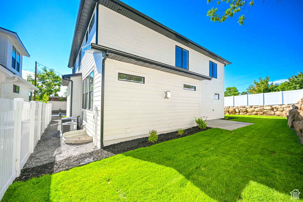 Rear view of house featuring central AC unit and a yard