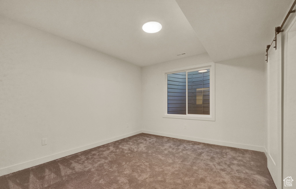 Empty room featuring a barn door and carpet