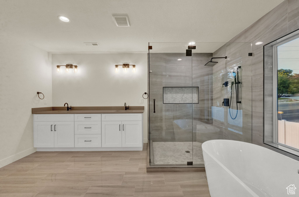 Bathroom featuring dual vanity, tile flooring, and plus walk in shower