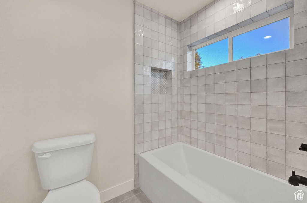 Bathroom with tiled shower / bath, toilet, and tile floors