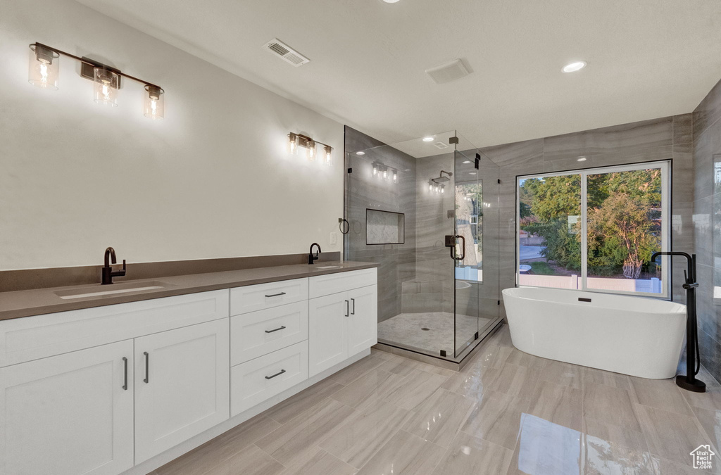 Bathroom featuring tile floors, dual bowl vanity, and plus walk in shower