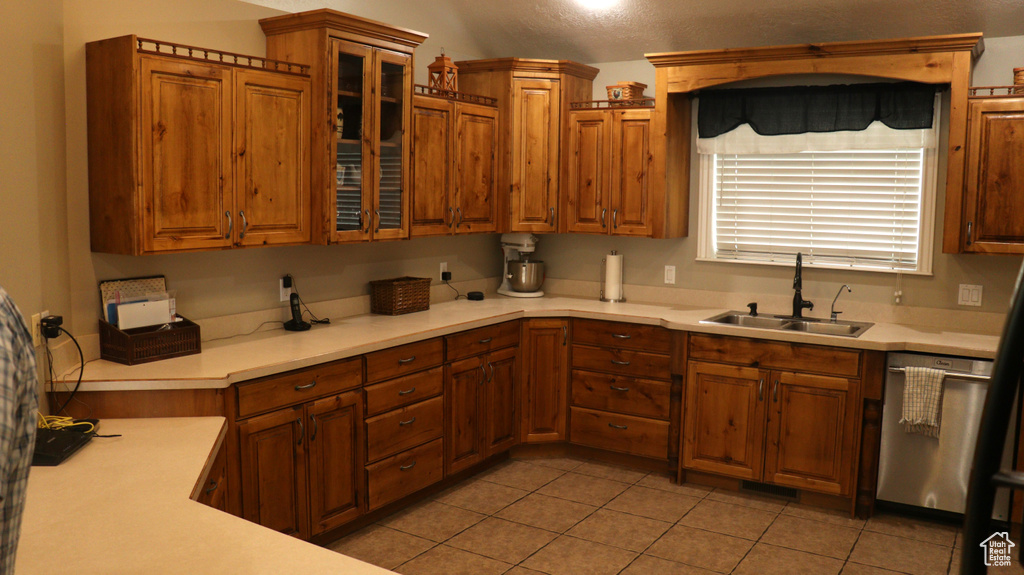 Kitchen featuring sink, dishwasher, and light tile floors