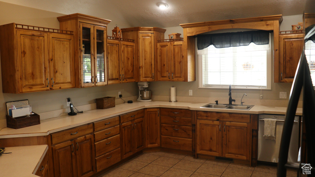 Kitchen featuring sink, dishwashing machine, and light tile flooring