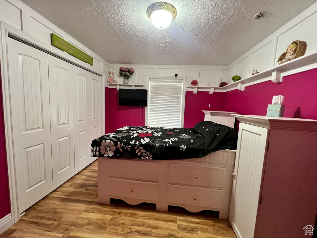 Bedroom featuring hardwood / wood-style flooring, a closet, and a textured ceiling