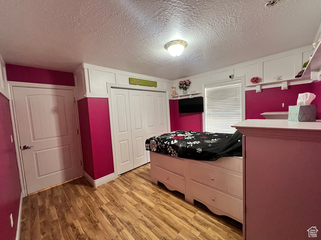 Kitchen with a textured ceiling, white cabinets, and light wood-type flooring