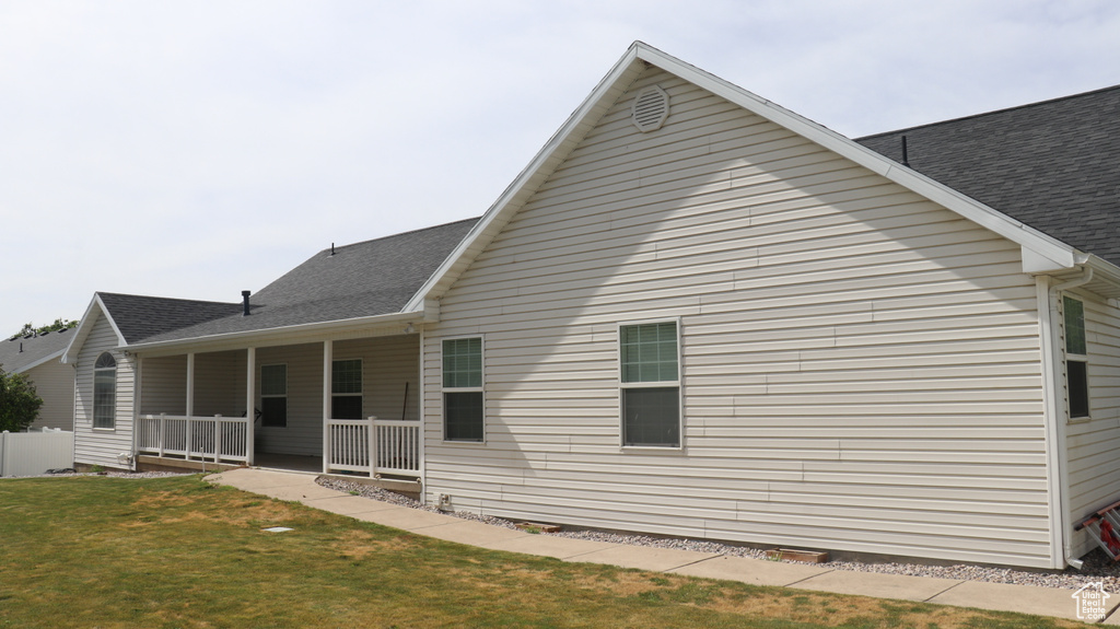 Rear view of house with covered porch and a lawn