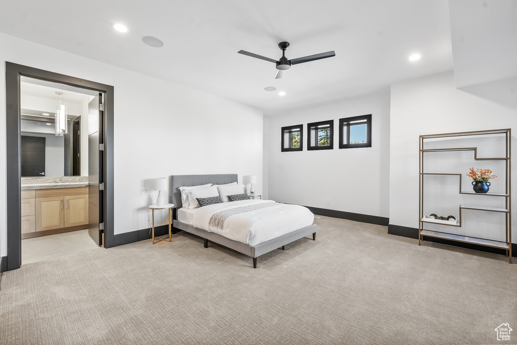 Bedroom with ceiling fan, connected bathroom, light colored carpet, and sink