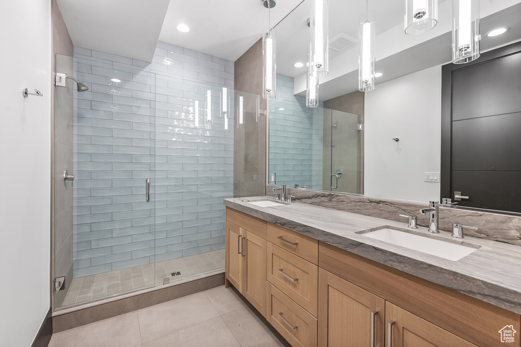 Bathroom with an enclosed shower, double sink vanity, and tile flooring