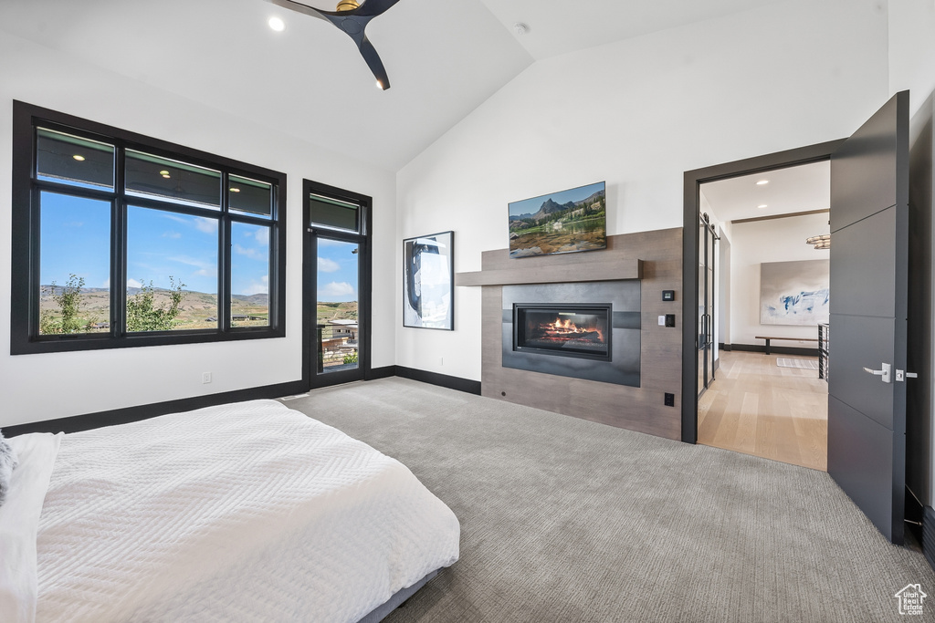 Carpeted bedroom with high vaulted ceiling, a tile fireplace, and ceiling fan