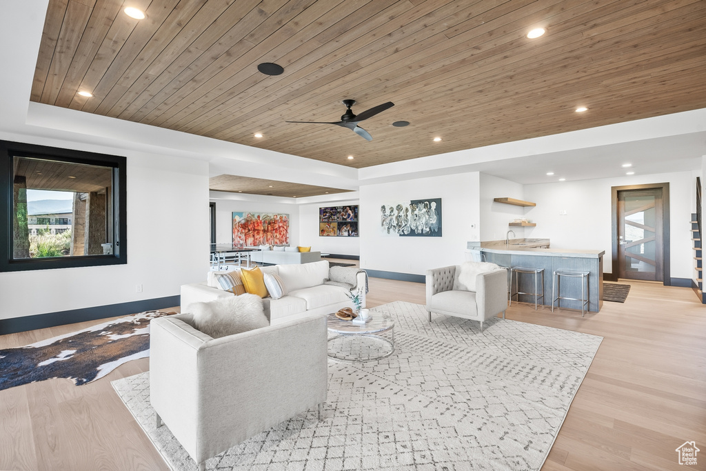 Living room with ceiling fan, light hardwood / wood-style flooring, and wood ceiling