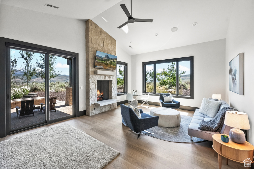 Living room featuring high vaulted ceiling, wood-type flooring, ceiling fan, and a fireplace