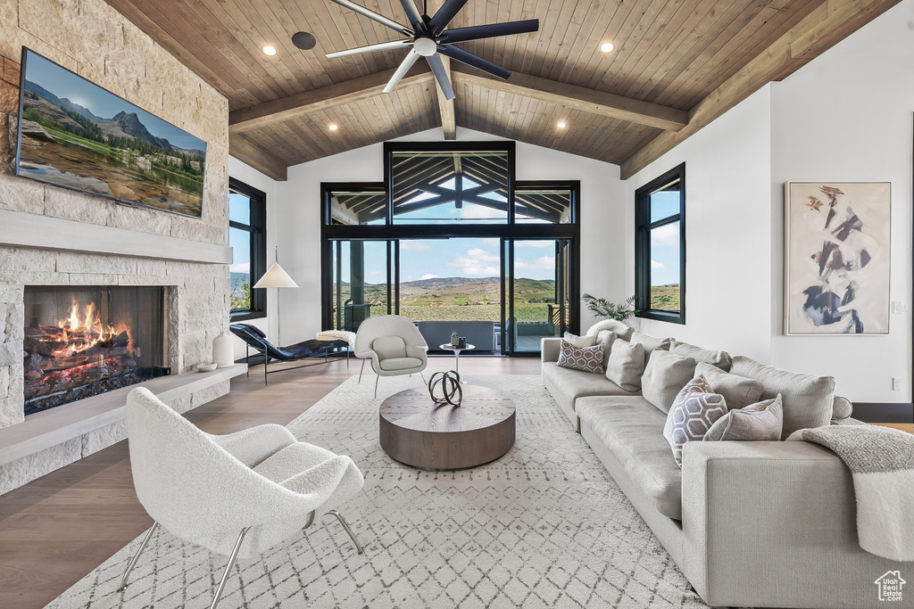 Living room with a stone fireplace, a healthy amount of sunlight, and wooden ceiling