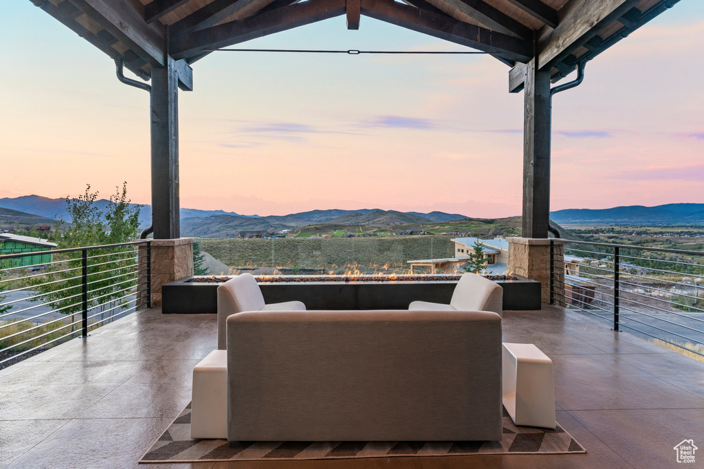 Patio terrace at dusk featuring a mountain view, outdoor lounge area, and a balcony