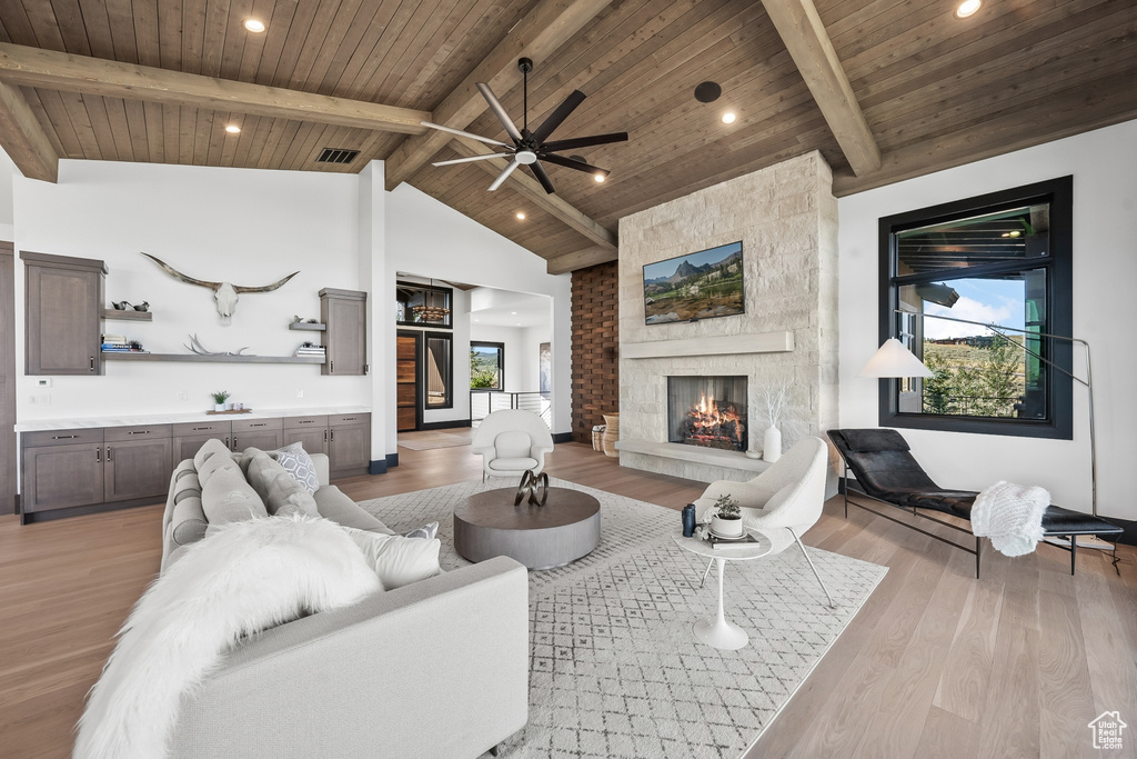 Living room featuring light hardwood / wood-style floors, a fireplace, ceiling fan, wooden ceiling, and lofted ceiling with beams