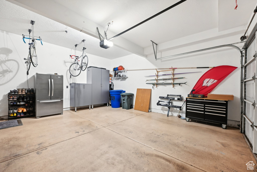 Garage with stainless steel fridge and a garage door opener