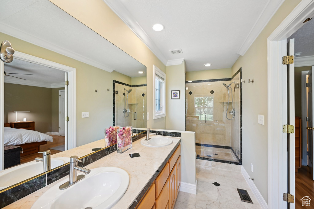 Bathroom featuring an enclosed shower, ornamental molding, ceiling fan, and double sink vanity