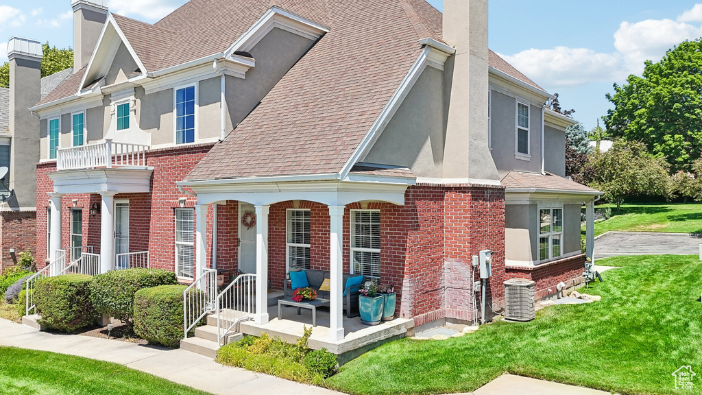 View of front facade featuring central AC, a balcony, and a front lawn