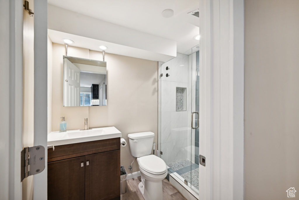 Bathroom with hardwood / wood-style floors, an enclosed shower, vanity, and toilet