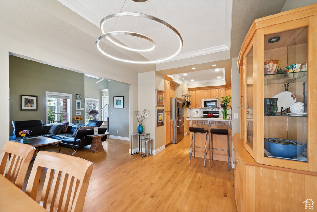 Dining room featuring ornamental molding, light hardwood / wood-style floors, and a tray ceiling