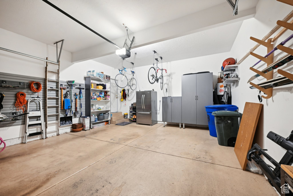 Garage with a workshop area, a garage door opener, and stainless steel refrigerator