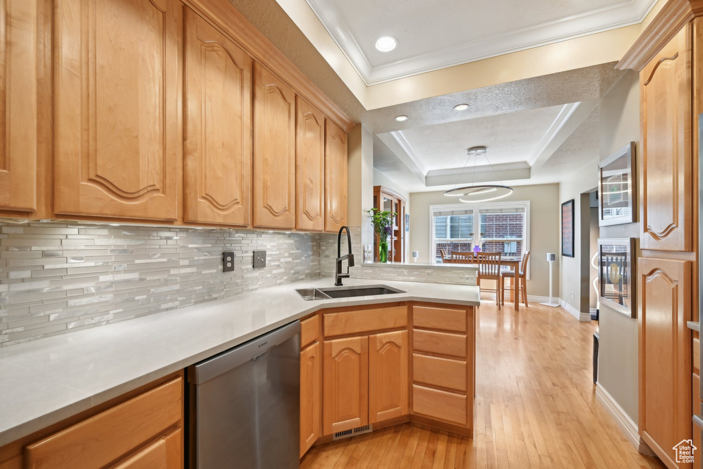 Kitchen with light hardwood / wood-style flooring, kitchen peninsula, dishwasher, backsplash, and sink