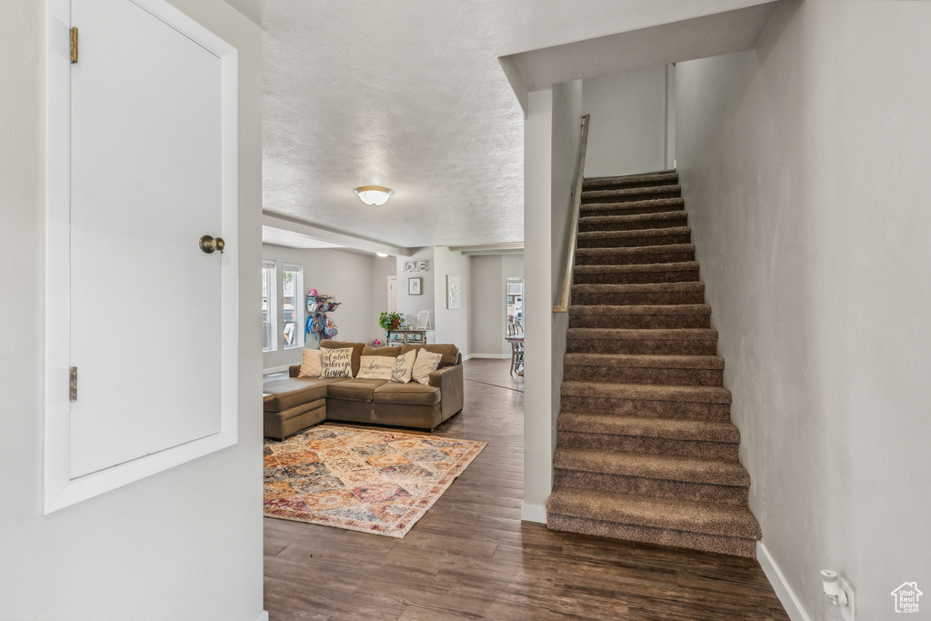 Stairway with a textured ceiling and dark wood-type flooring