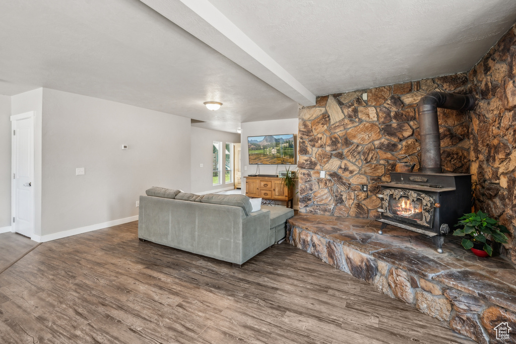 Living room featuring beamed ceiling, hardwood / wood-style flooring, and a wood stove