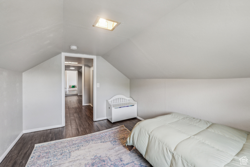 Bedroom with vaulted ceiling and dark wood-type flooring