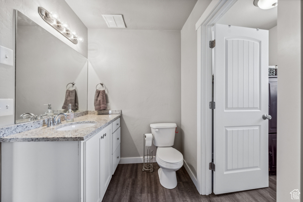 Bathroom featuring hardwood / wood-style flooring, oversized vanity, and toilet