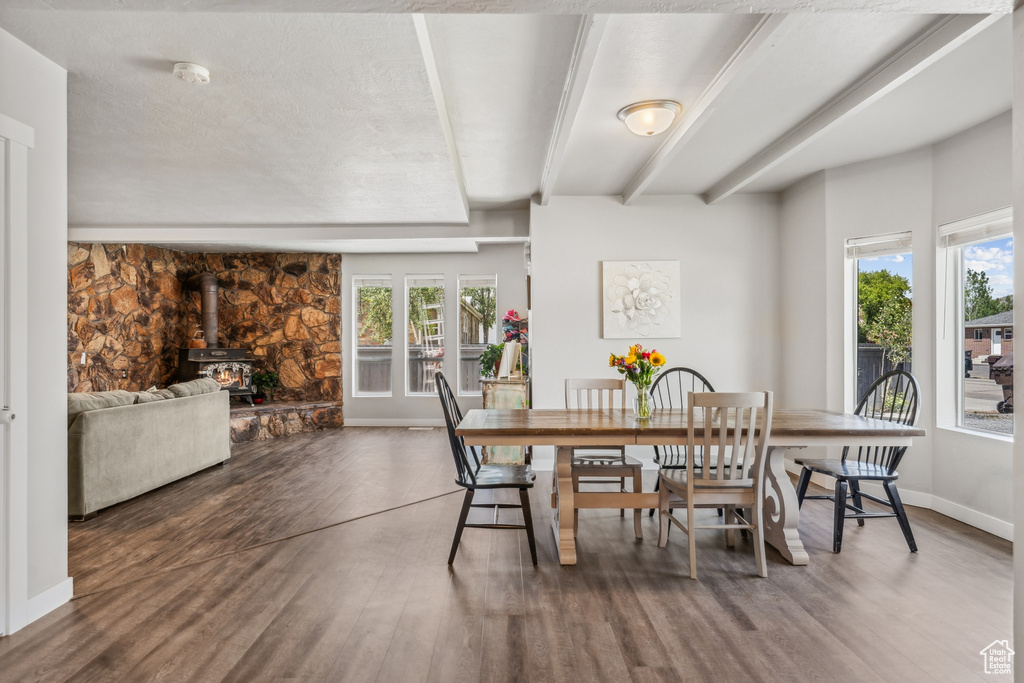 Dining room featuring a healthy amount of sunlight, wood-type flooring, and a wood stove