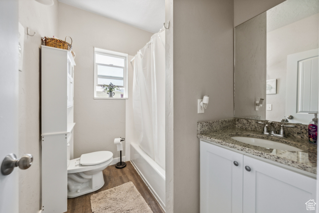 Full bathroom featuring shower / tub combo, vanity, toilet, and hardwood / wood-style floors