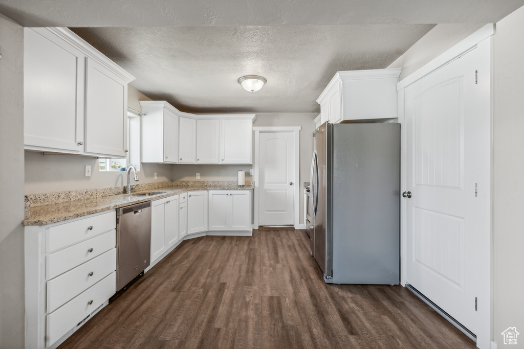 Kitchen with sink, dark hardwood / wood-style flooring, white cabinetry, and appliances with stainless steel finishes