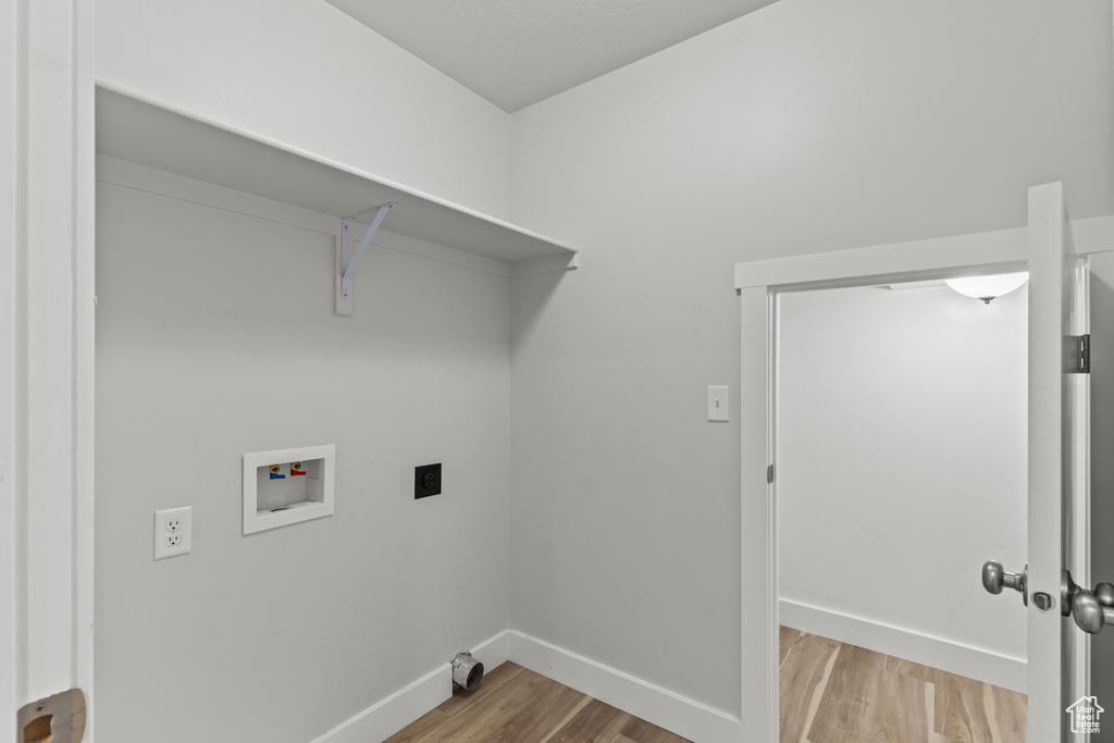 Washroom with hookup for a washing machine, light hardwood / wood-style flooring, and hookup for an electric dryer