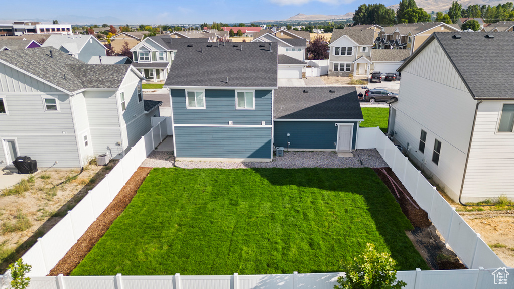 Rear view of house featuring a lawn and central AC