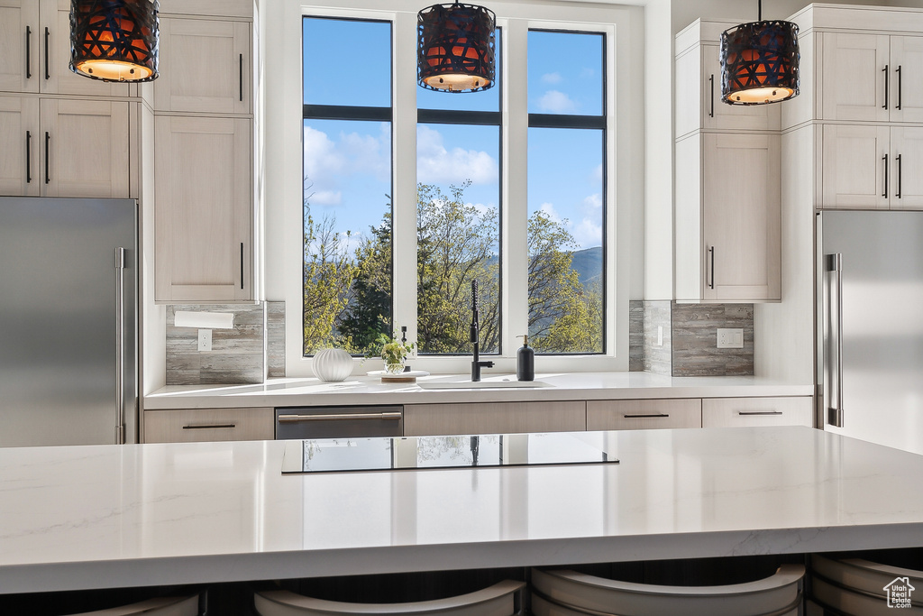 Kitchen featuring high end fridge, tasteful backsplash, and a sink